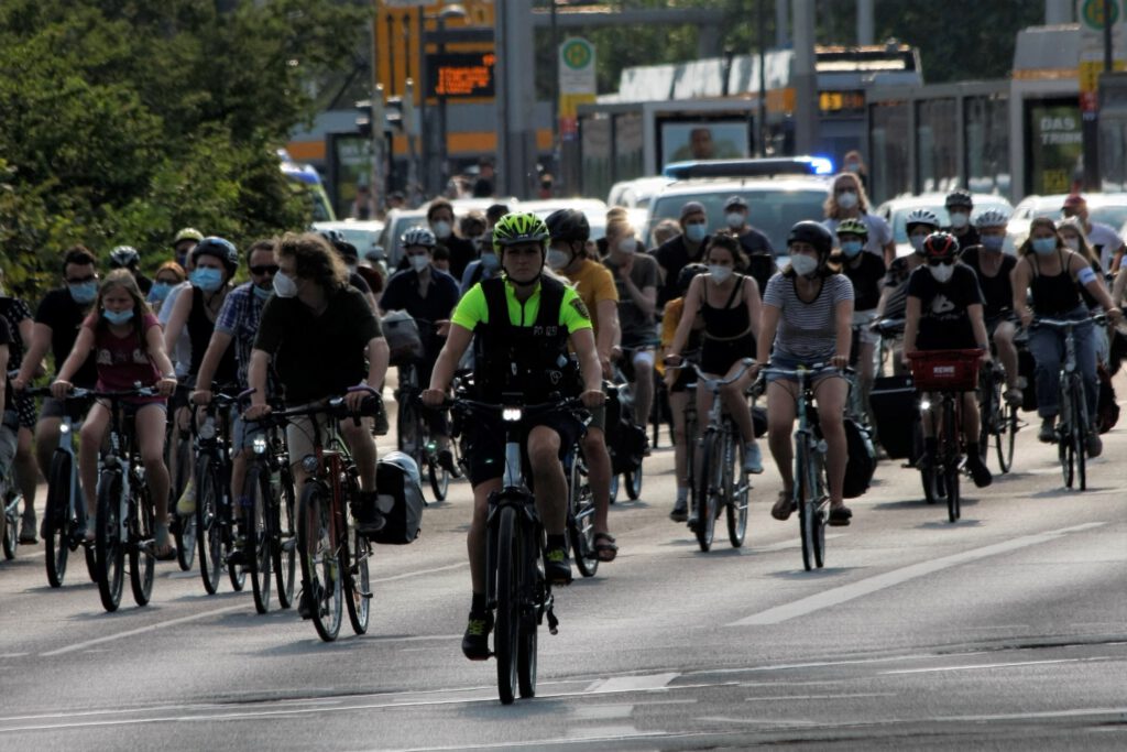 Mehrere Personen fahren mit dem Fahrrad auf dem Innenstadtring. Sie werden von Fahrrad-Polizist*innen eskortiert.